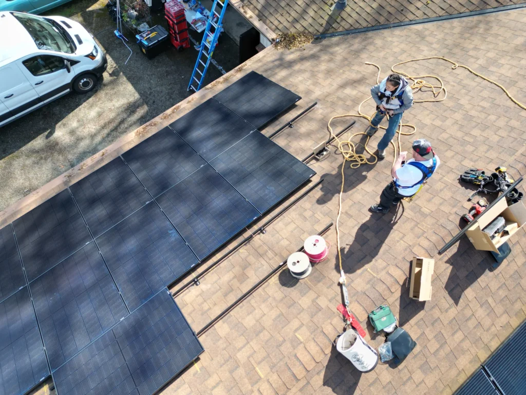 Two solar panel installers working on a house roof in Washington